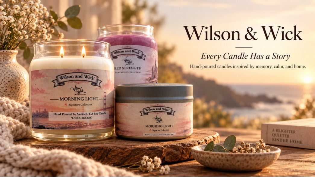 Three Wilson & Wick candles displayed on a rustic wooden surface with a cozy outdoor sunset background. The set includes a lit glass jar candle labeled 'Morning Light' with white wax, a purple wax jar labeled 'Her Strength', and a tin candle labeled 'Morning Light' with gray lid.